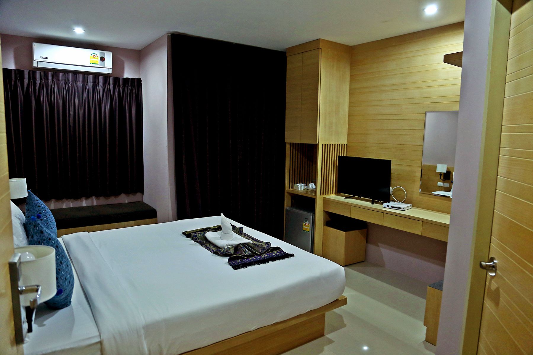 Habitación de hotel con cama, escritorio, computadora, televisor y minibar.