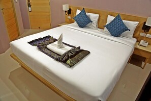 A neatly made bed with a white comforter, blue patterned pillows, and a decorative throw. - Rayaan 6 Guesthouse (Patong)