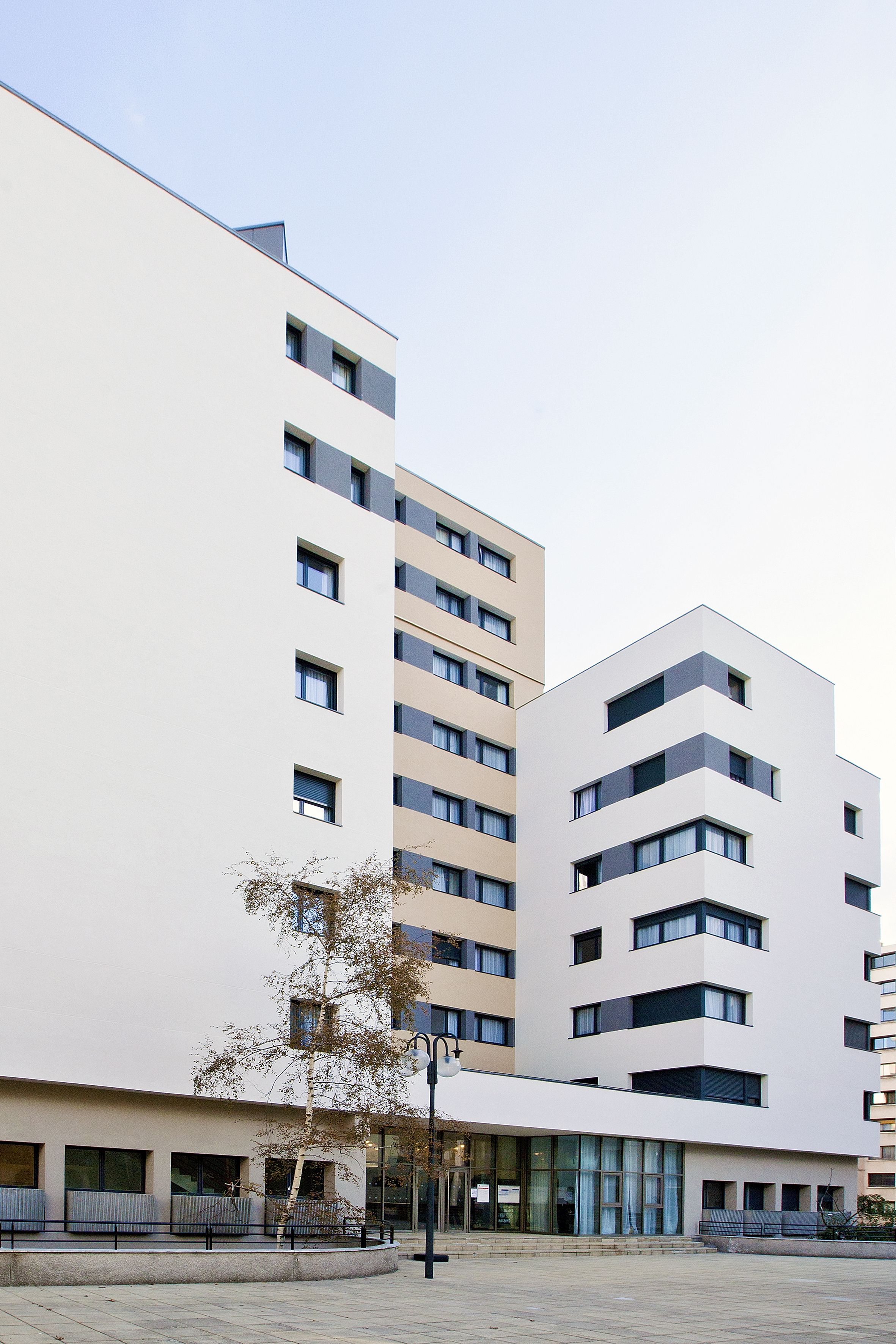 Ein modernes Gebäude mit mehreren Stockwerken, großen Fenstern und einer glatten Fassade.