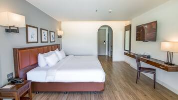 Habitación de hotel con una cama grande, un escritorio con una silla, un televisor y cuadros en la pared.