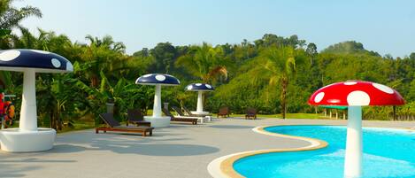 A pool area with lounge chairs and mushroom-shaped umbrellas.