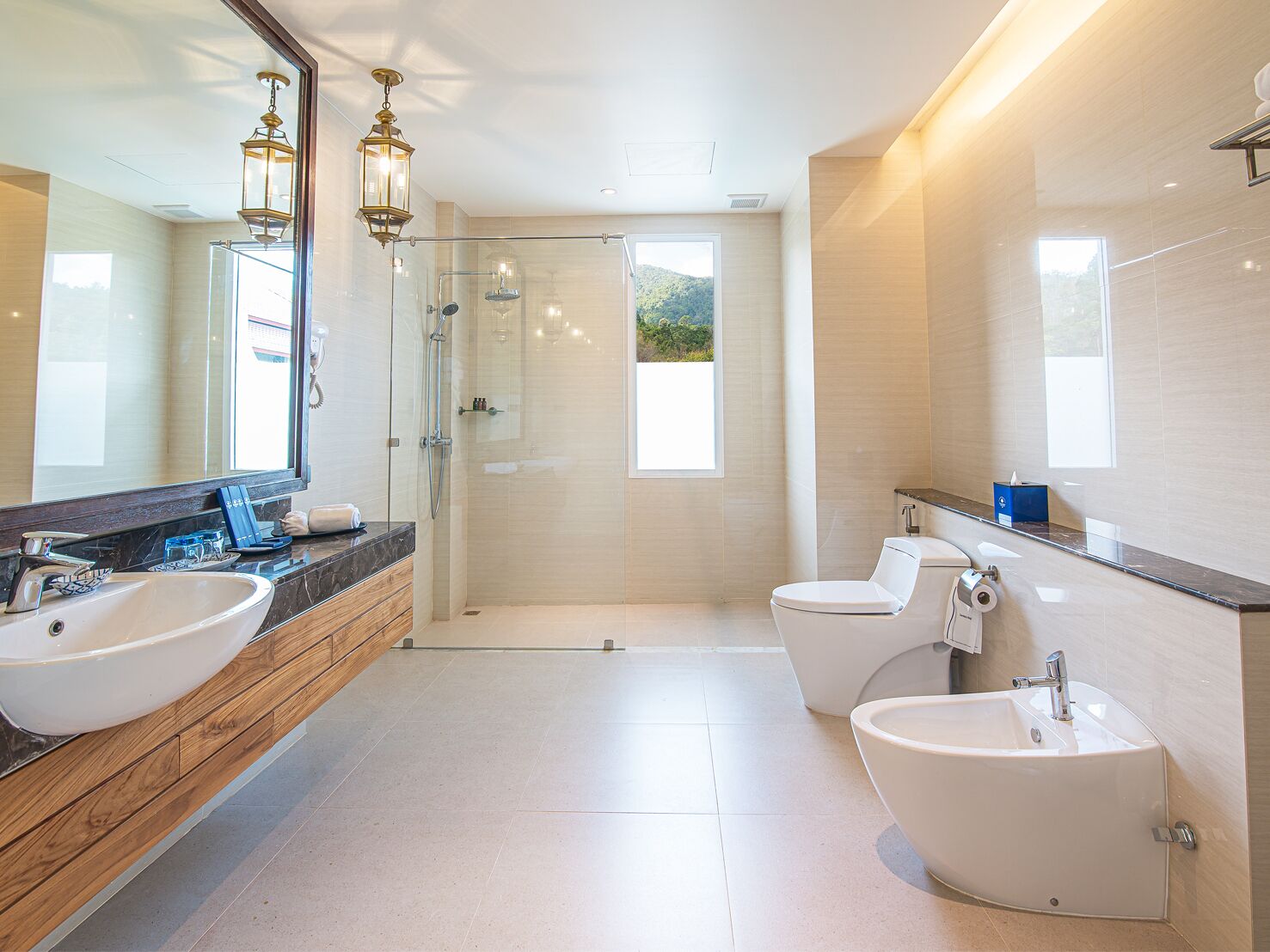 A modern bathroom with a large mirror, two sinks, a shower, and a toilet.