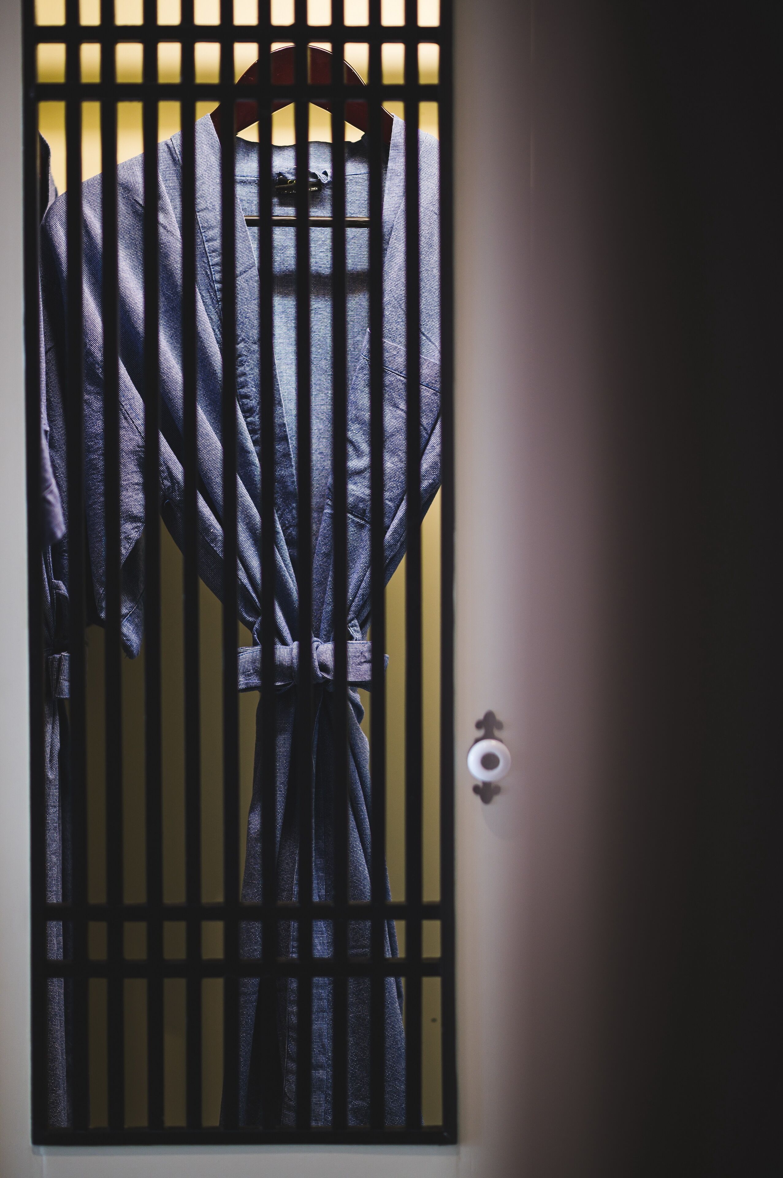 A room with a barred window, a door with a lock, and a small heart-shaped decoration on the wall.