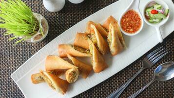 A plate of spring rolls with a side of dipping sauce and salad.