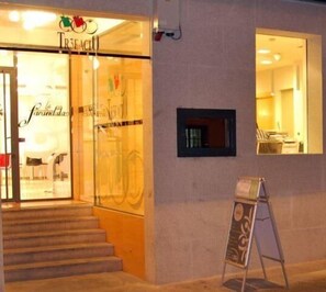A storefront with a glass entrance, a staircase leading up, and a small window on the wall. - Hotel Trefacio (Zamora)