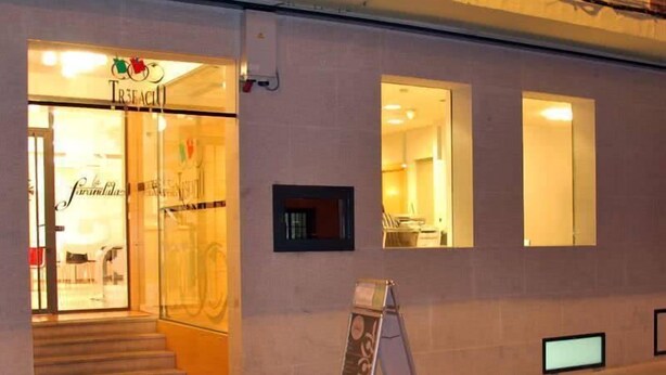 Un edificio con un escaparate que dice 'TR3FACII' y un cartel en el exterior.