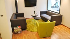 Una sala de estar moderna con dos sofás, una mesita redonda y un televisor montado en la pared.