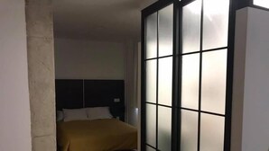 Un dormitorio con cama, cabecero y puerta corrediza con paneles de vidrio esmerilado.
