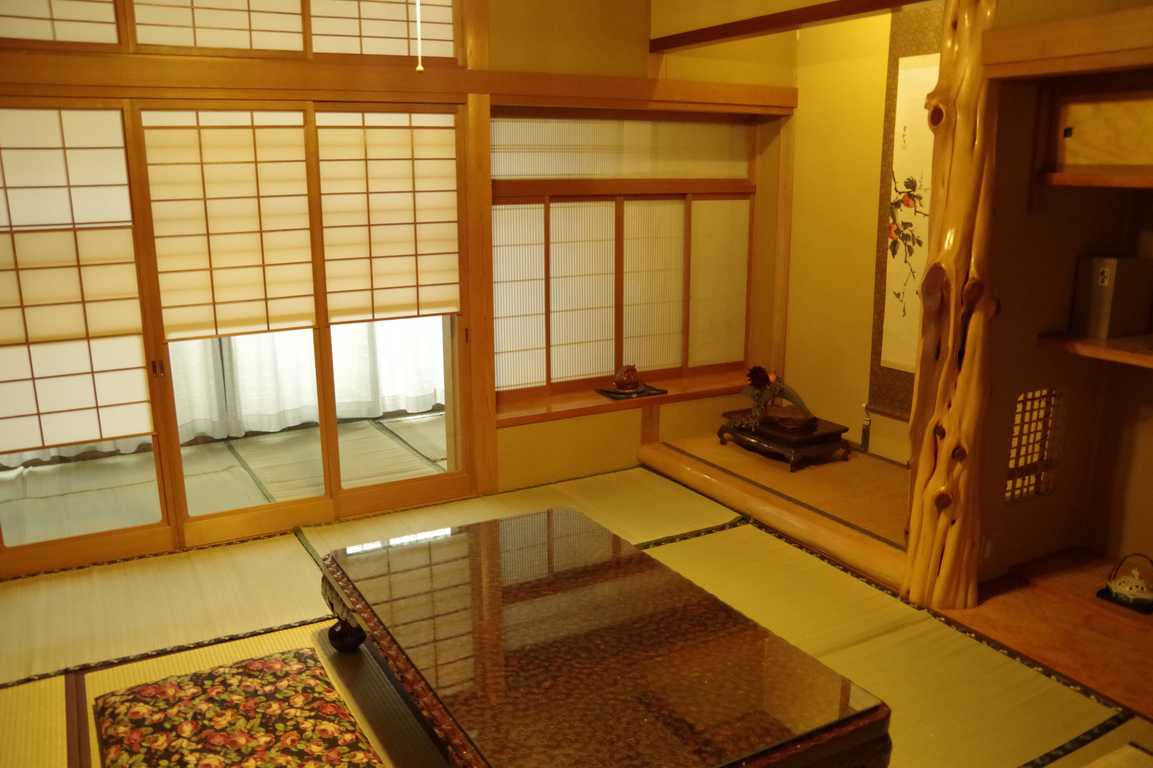 A traditional Japanese room with tatami flooring, sliding shoji doors, and a low wooden table.