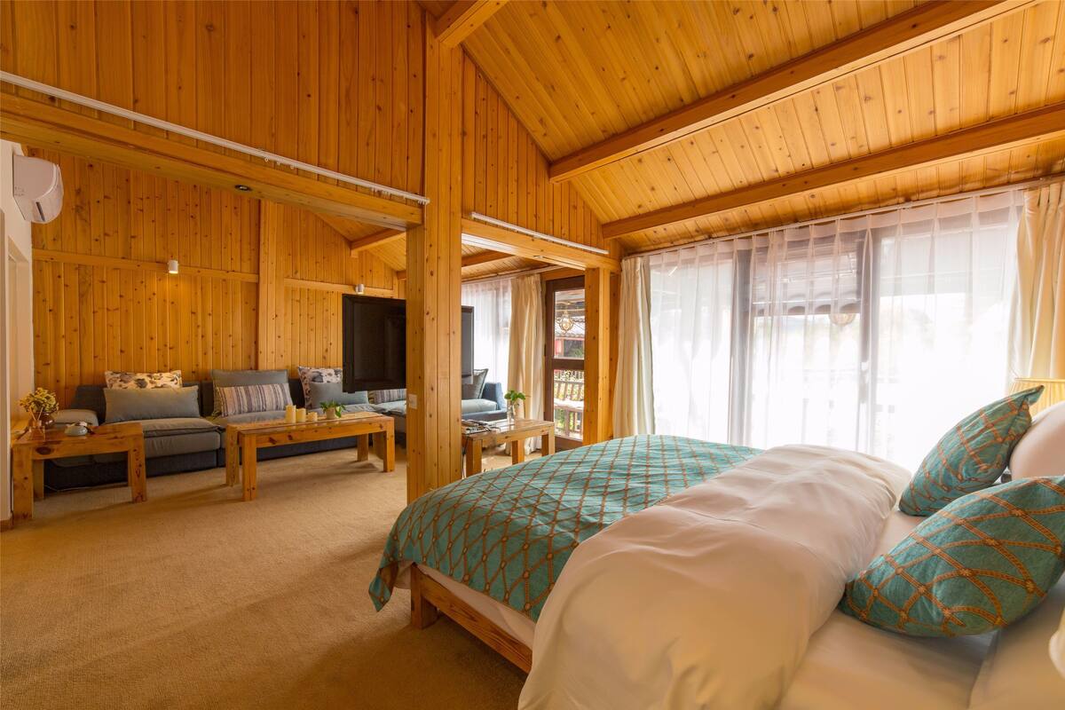 Interior de una cabaña de madera con una cama, un sofá y un televisor.