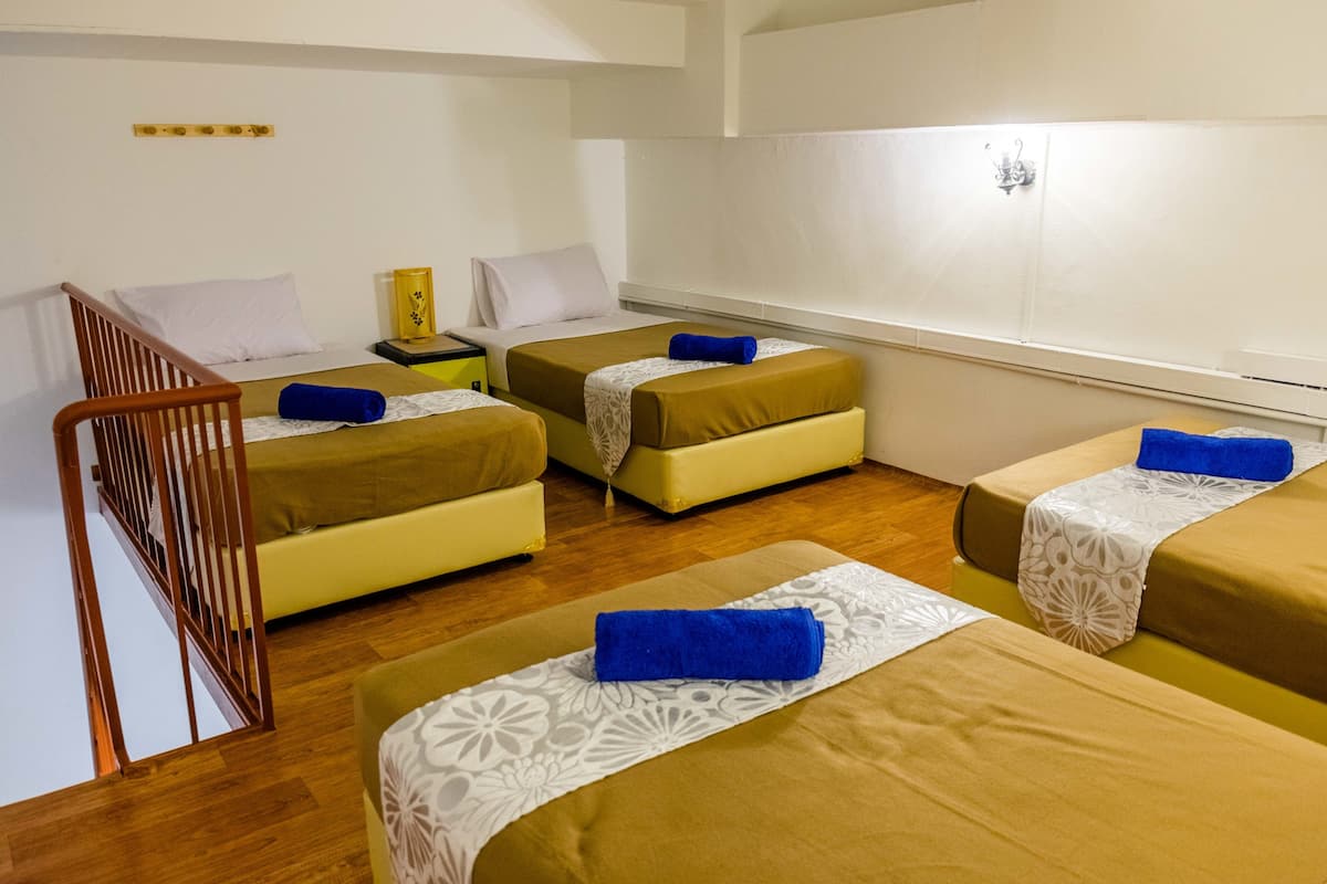 A hotel room with two single beds, a wooden chair, a small table, and a window.