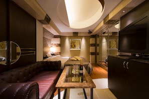 A modern hotel room with a sofa, a small table with glasses and a bottle, a bed, a TV, and a decorative wall. - HOTEL THE HOTEL Shinjuku Kabukicho - Adults Only (Tokyo)