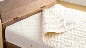 A bed with a quilted mattress and a wooden headboard.