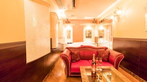 A hotel room with a red sofa, a glass coffee table, and a minibar.