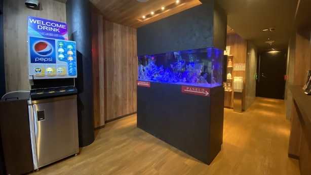 A hallway with a vending machine, a sign for a welcome drink, and an aquarium display.