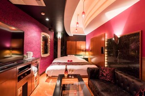 Una habitación de hotel con una cama, un televisor, un sofá y un minibar.