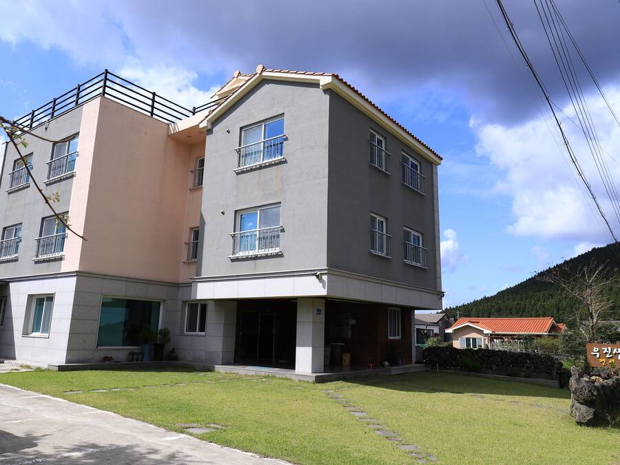 Een woongebouw met twee verdiepingen, een plat dak, meerdere ramen en een balkon.