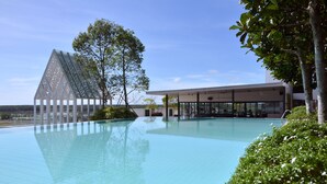 A modern hotel with a large swimming pool, a distinctive triangular glass structure, and lush greenery. - UCSI Hotel Kuching (Kuching)