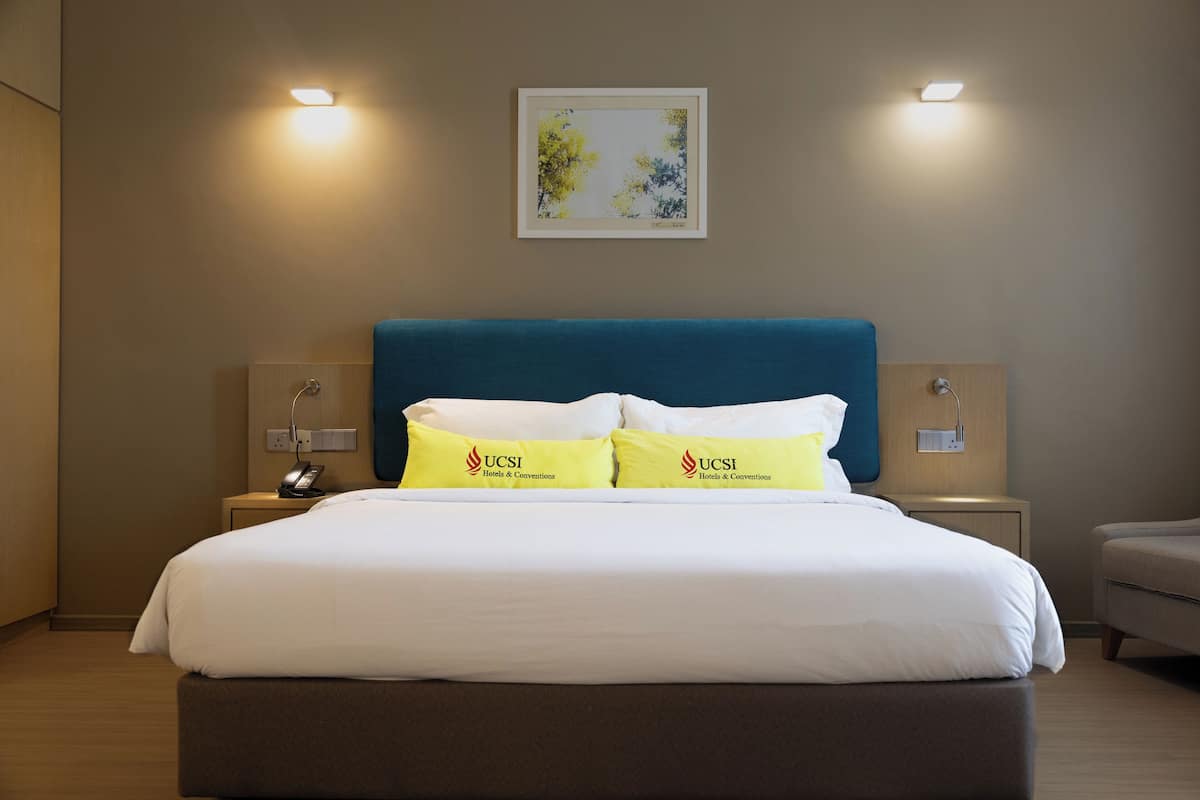 A hotel room with a large bed, two bedside tables, a nightstand, and a framed picture on the wall.