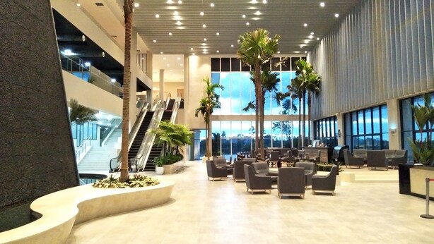 A spacious lobby with multiple levels, palm trees, and seating areas. - UCSI Hotel Kuching (Kuching)