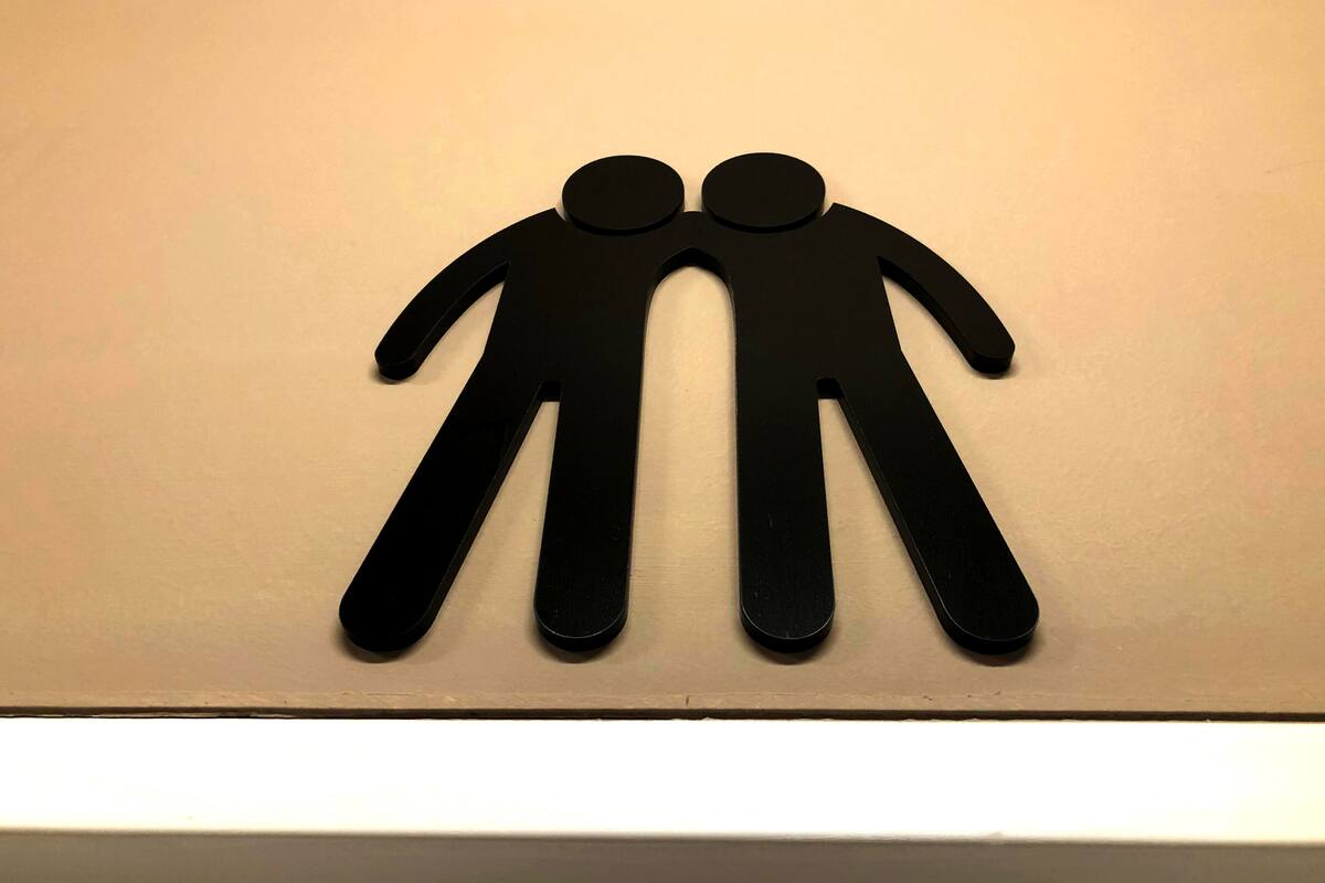 A black sign with two figures holding hands on a white wall.