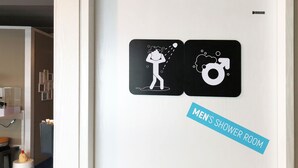 A men's shower room with a sign indicating it. - Sohostel Korea (Busan)