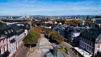 An aerial view of a city square with historic buildings, a central fountain, and tram tracks.