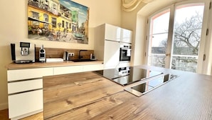A modern kitchen with a wooden countertop, white cabinets, and a large window with a view of the city. - The Apartment Suite Osteiner Hof (Mainz)