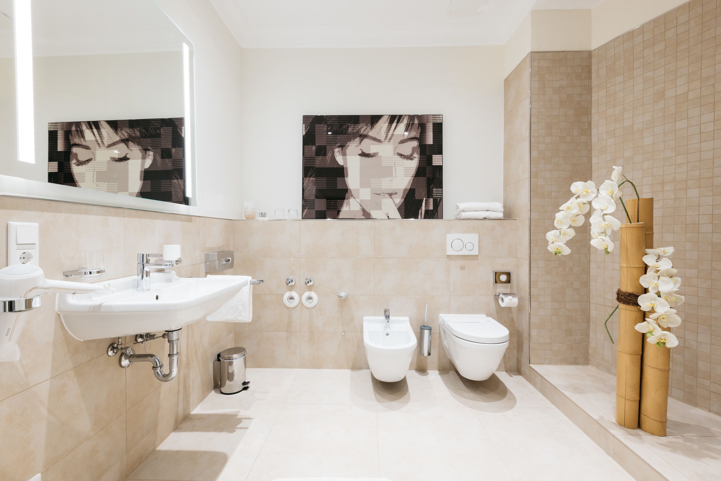 Un baño moderno con lavamanos, bidé, inodoro y espejo.
