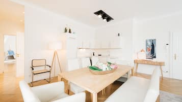 Una cucina moderna con mobili bianchi, un tavolo da pranzo in legno e una ciotola con fiori.