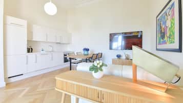 A modern kitchen with white cabinets, a wooden dining table, and a vase with flowers.