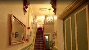 A staircase with patterned carpet, a chandelier, and framed pictures on the walls. - Athol Guest House (Filey)