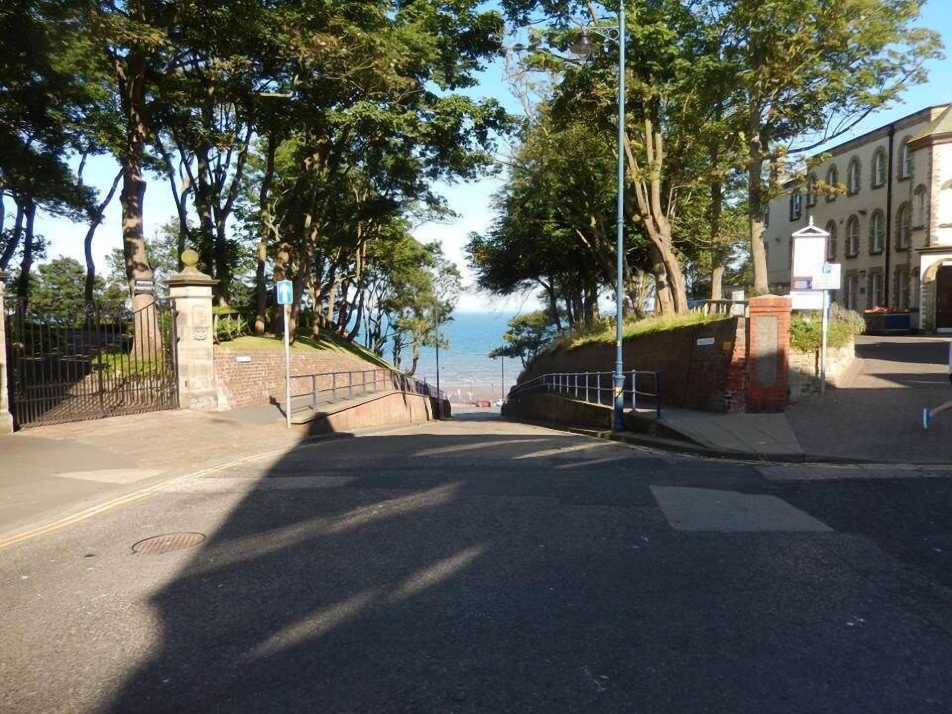 A road leading to a building with a view of the sea.