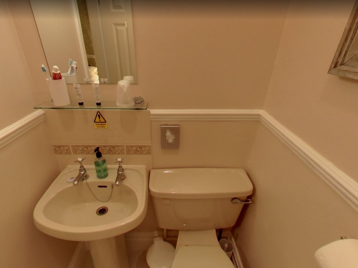 A bathroom with a sink, toilet, and a caution sign on the mirror.