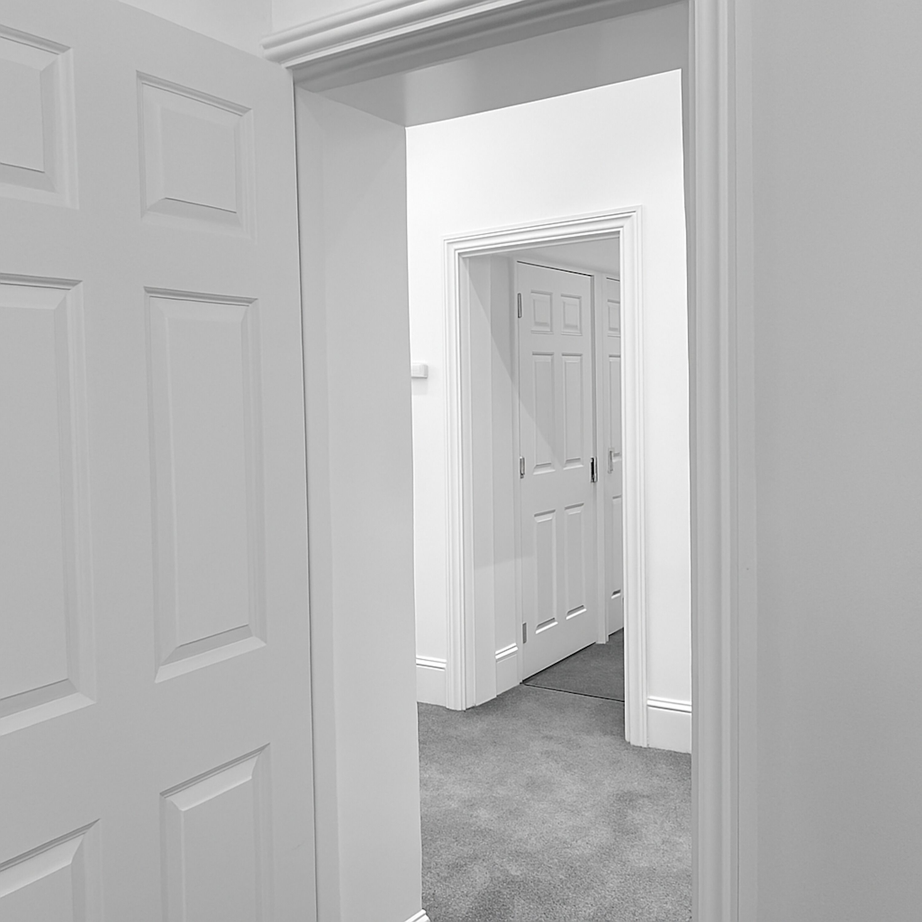 A hallway with white doors and a carpeted floor.