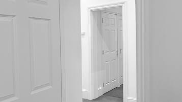 A hallway with white doors and a carpeted floor.