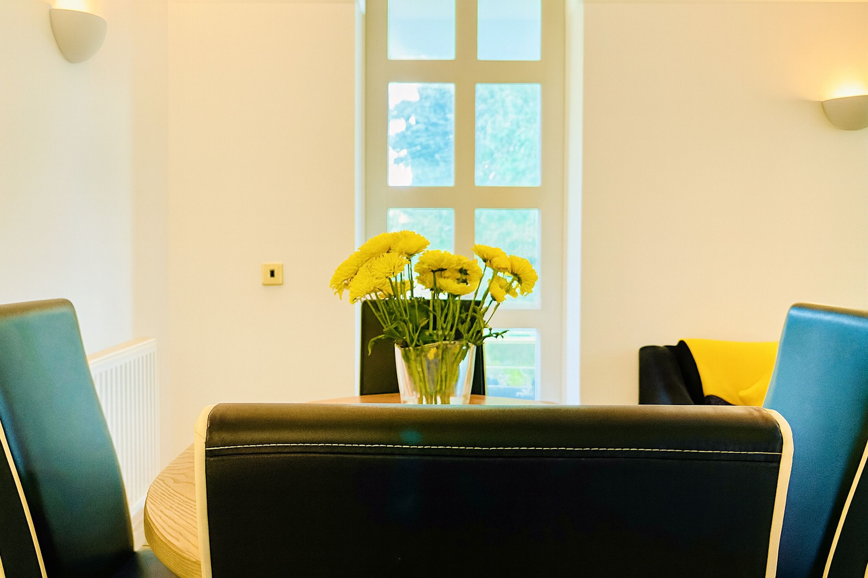 A room with a table in the center, two chairs on either side, and a window with a view of trees.