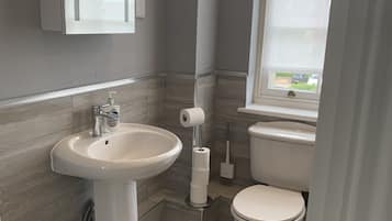 Un baño moderno con un lavamanos, inodoro y ventana que proporciona luz natural.