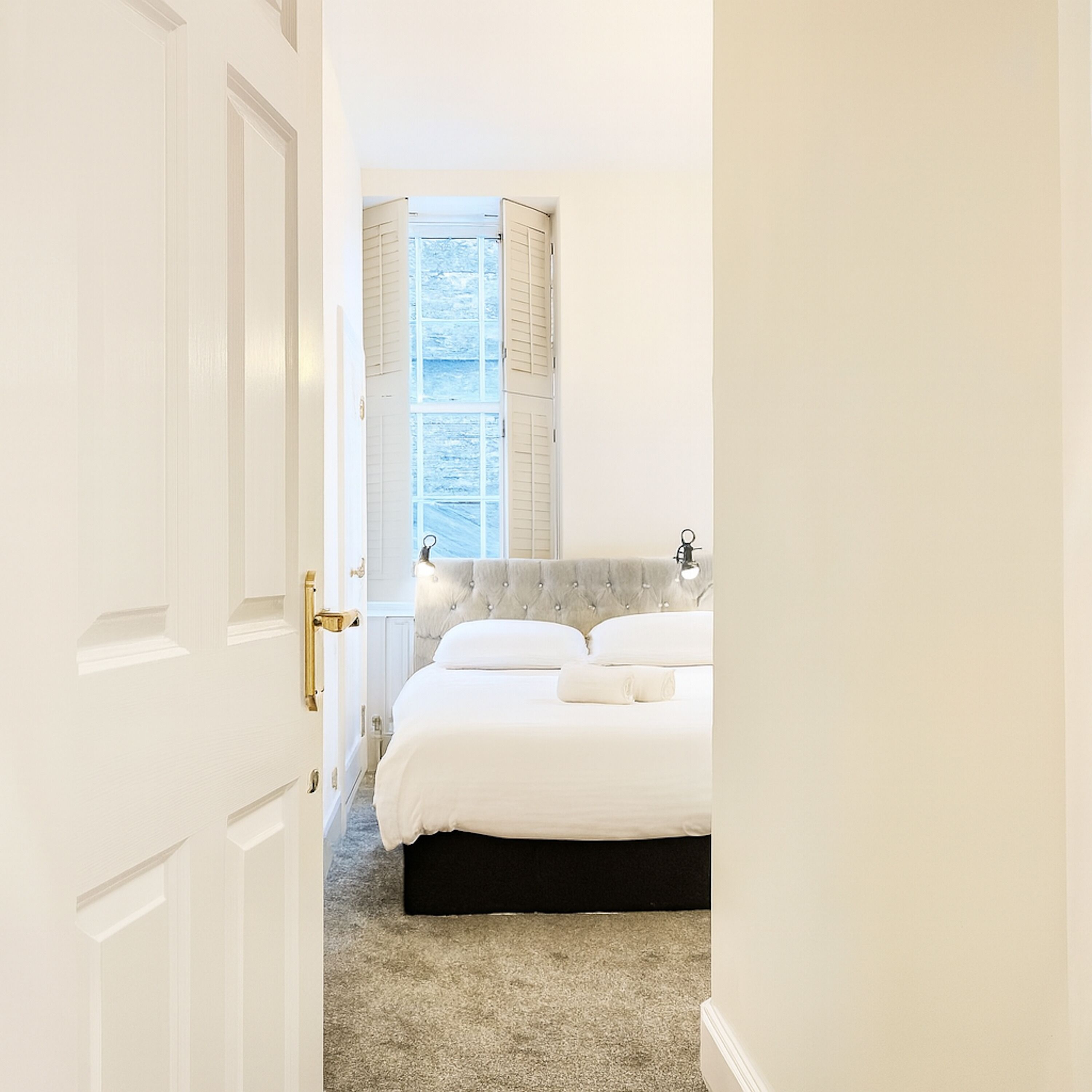 Ein Schlafzimmer mit Bett, einem Fenster mit Rollläden und einer Tür.