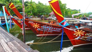 Una hilera de botes tradicionales amarrados a un muelle con una pasarela de madera.