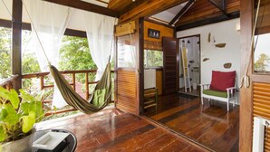 Interior de madera con una hamaca, una pequeña mesa y una silla.