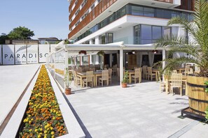 Ett modernt hotell med uteservering och en blomsterrabatt.
