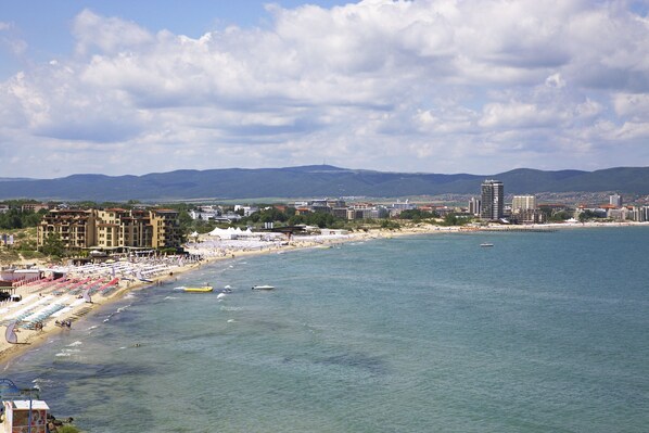 A coastal cityscape with a beach, buildings, and mountains in the background. - Paradiso Apartcomplex (Nessebar)