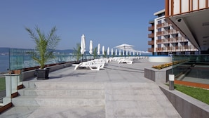 A rooftop terrace with lounge chairs, umbrellas, and a view of the sea. - Paradiso Apartcomplex (Nessebar)