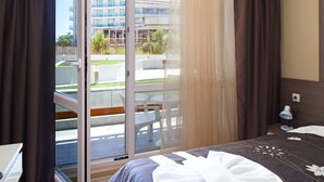 Habitació d'hotel amb llit, escriptori, cadira i balcó que té taula i cadires.