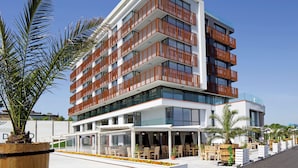 A multi-story hotel with balconies, outdoor seating, and palm trees. - Paradiso Apartcomplex (Nessebar)