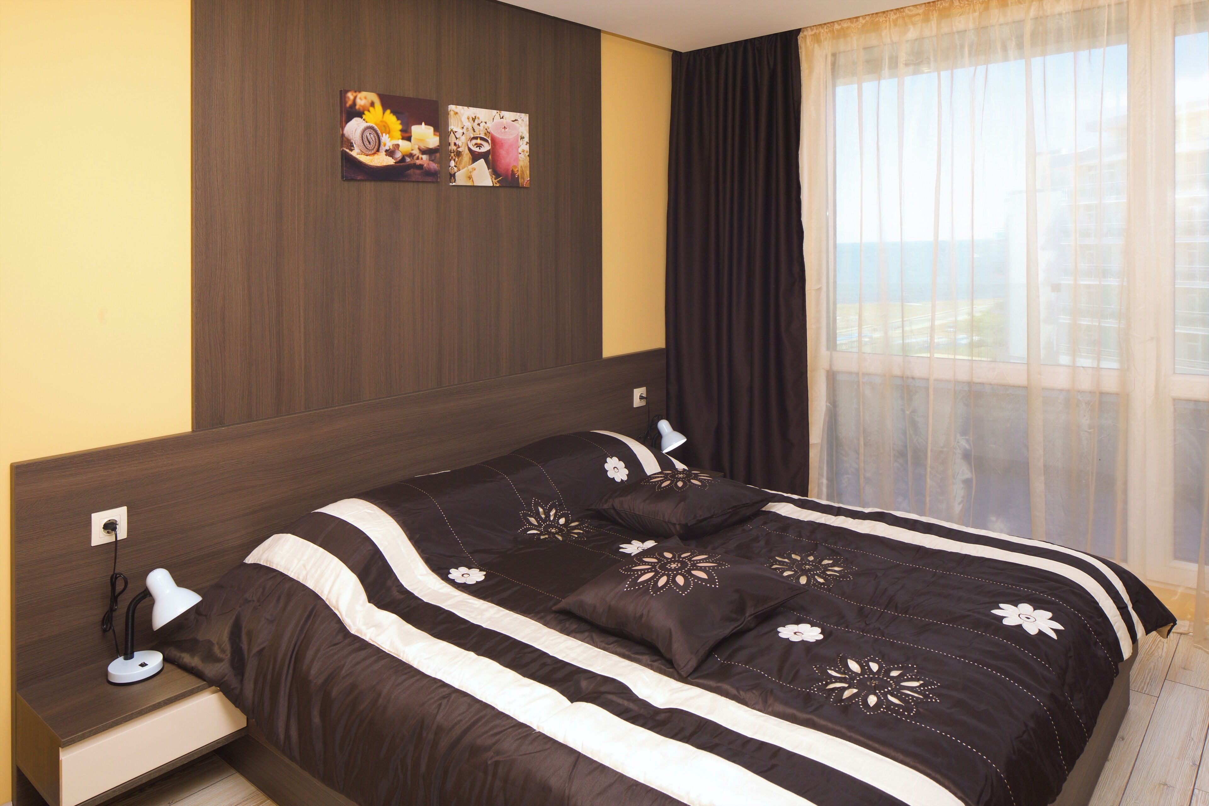 A neatly made bed with a dark and light striped bedspread, a bedside lamp, and a wall-mounted picture.