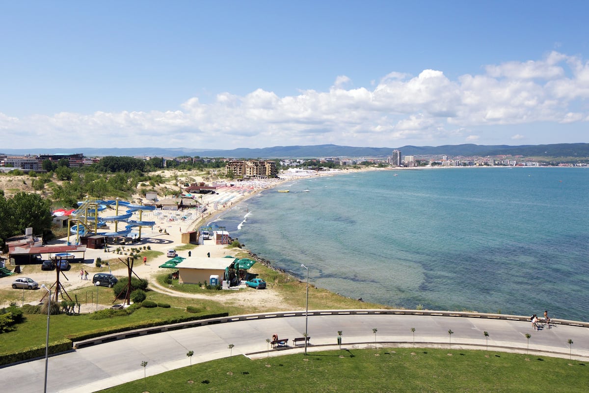 A coastal area with a beach, water, and a road.