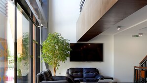 Un vestíbul modern amb una planta gran, seients de cuir i un televisió de pantalla plana.