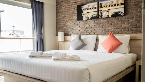 A hotel room with a bed, pillows, and a view of the city through the window. - Chinotel (Phuket)